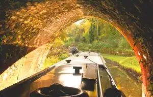 Narrowboat navigating a dark canal tunnel